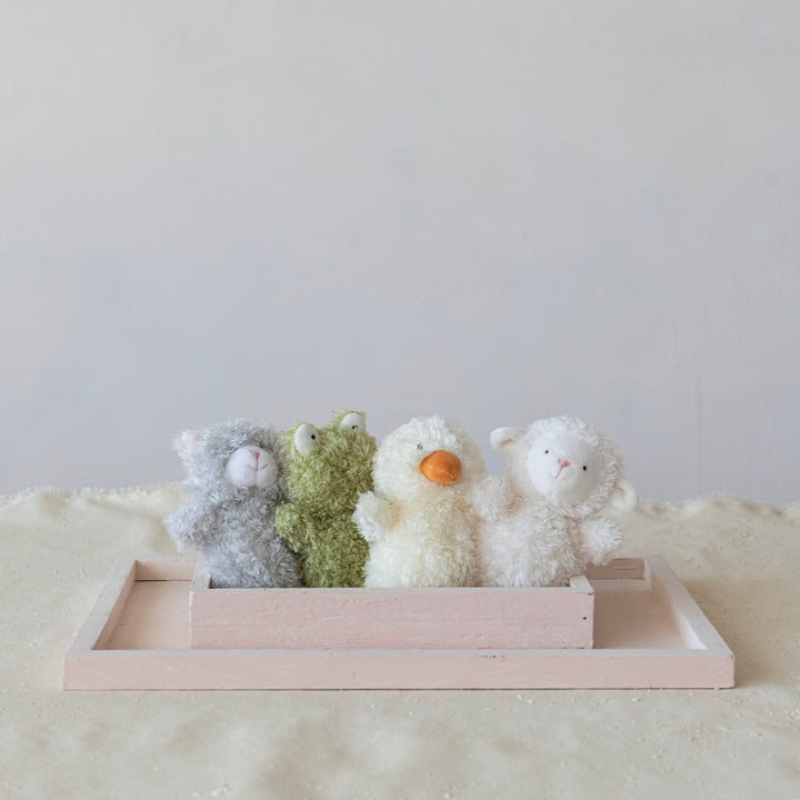 Four stuffed animals in a wooden tray on a light surface with a white background