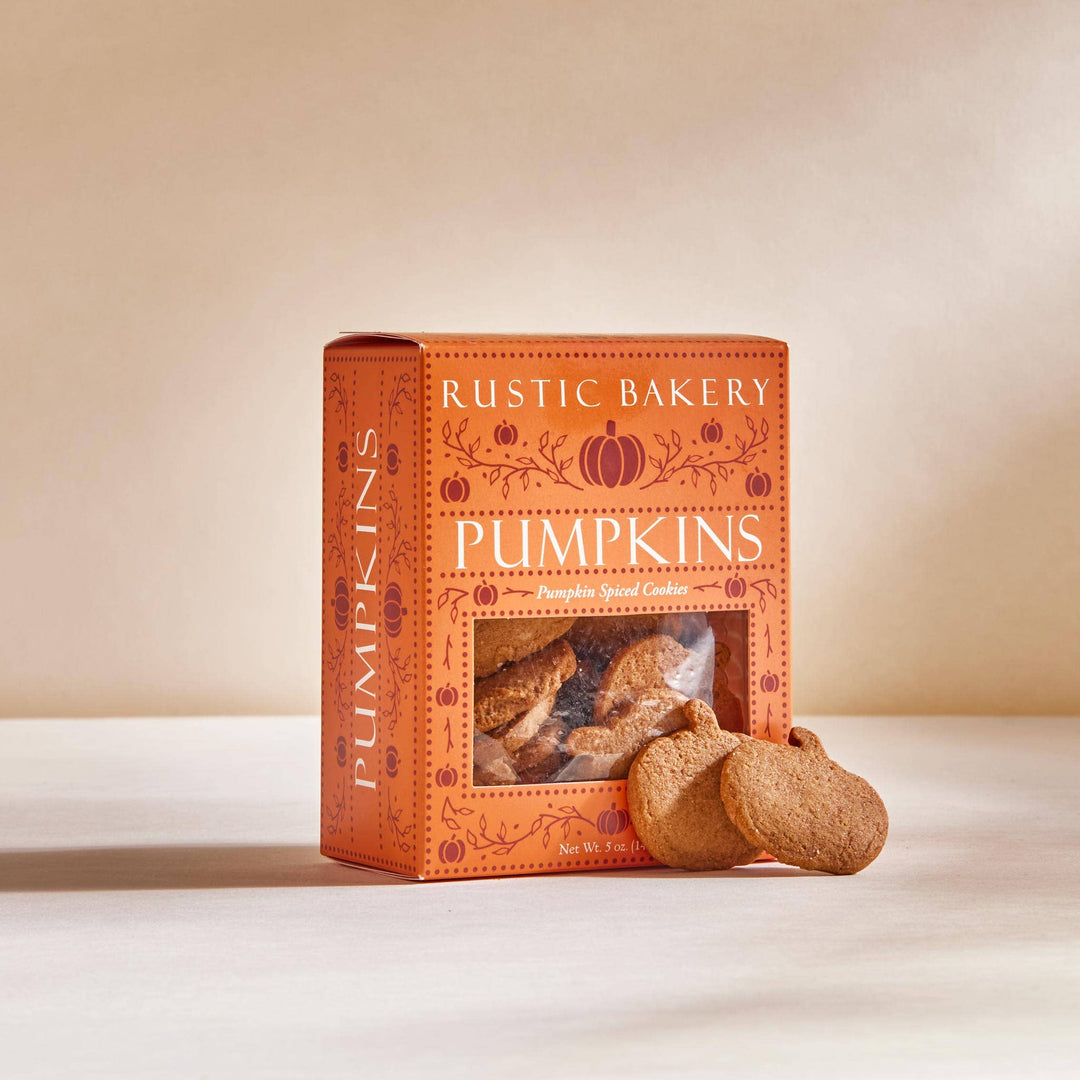 Box of Rustic Bakery Pumpkins cookies with a pumpkin-shaped cookie on a beige background