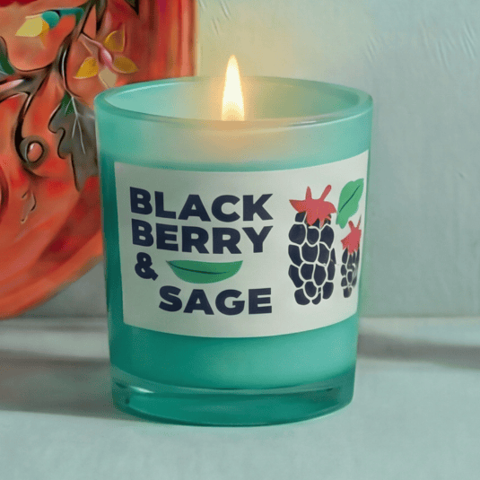 Teal candle labeled 'Blackberry & Sage' with a decorative background