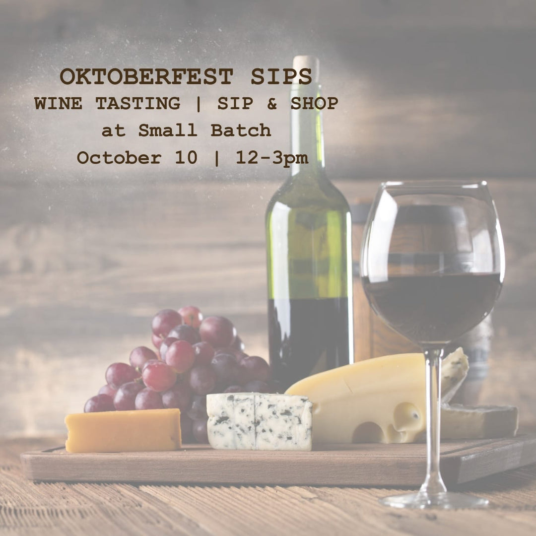 Promotional graphic for 'Oktoberfest Sips' wine tasting at Small Batch, featuring a bottle of wine, a glass of red wine, grapes, and cheese on a wooden board against a rustic wooden background.