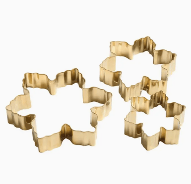 Set of gold metal cookie cutters shaped like snowflakes on a white background
