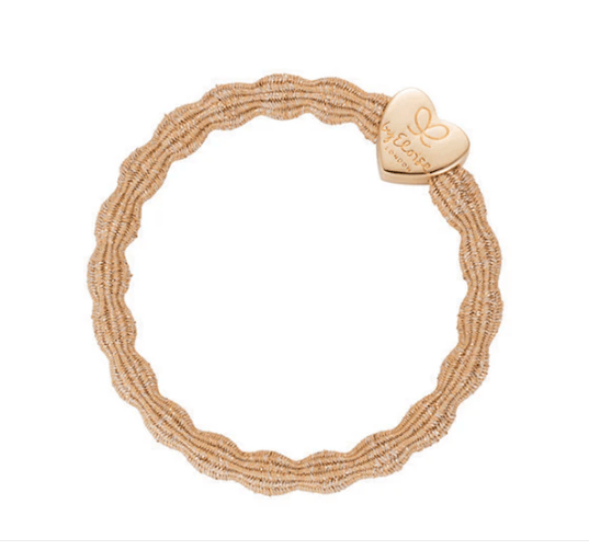 Beige bracelet with a heart-shaped charm on a white background