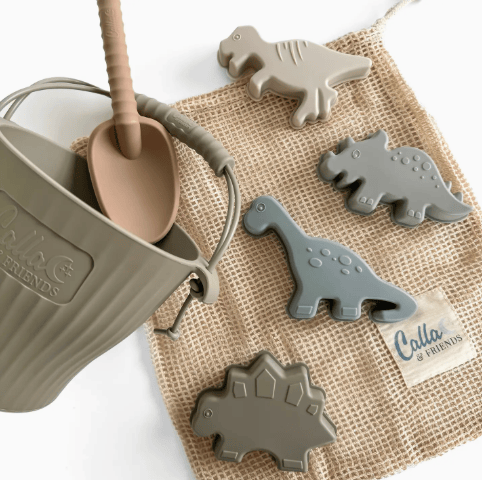 Children's playset with dinosaur toys and a sand pail on a burlap bag.