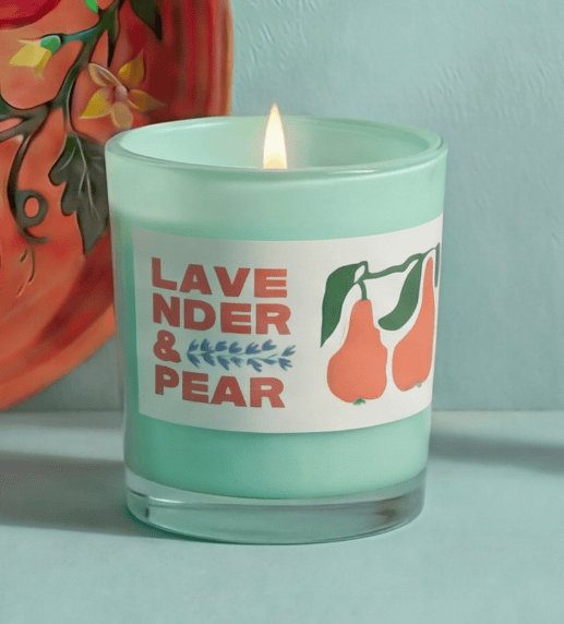 Candle in a green jar with a label reading 'Lavender & Pear' on a light blue background.