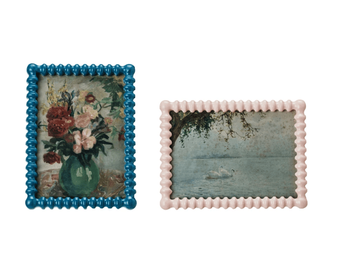 Two decorative picture frames with floral and landscape designs on a white background.