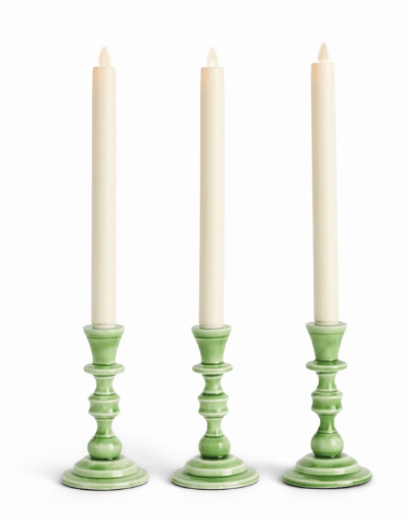 Three green candle holders with white candles on a white background
