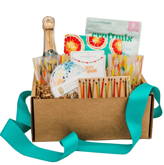 Gift basket with a bottle of champagne, craft supplies, and other items on a white background