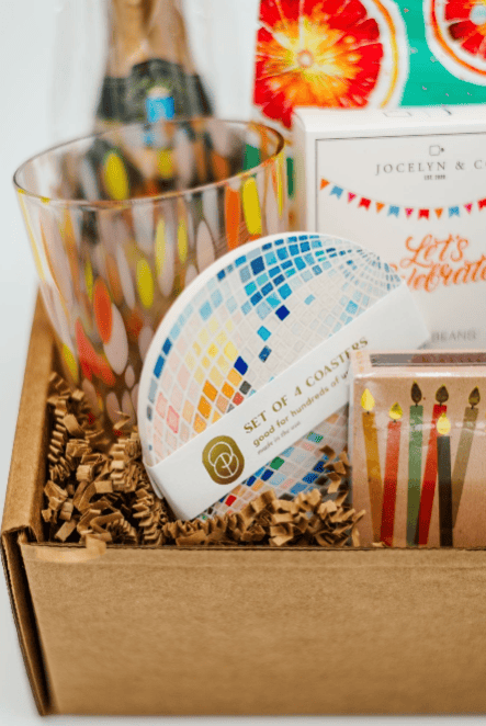Gift box with colorful coasters, candles, and other items on a white background
