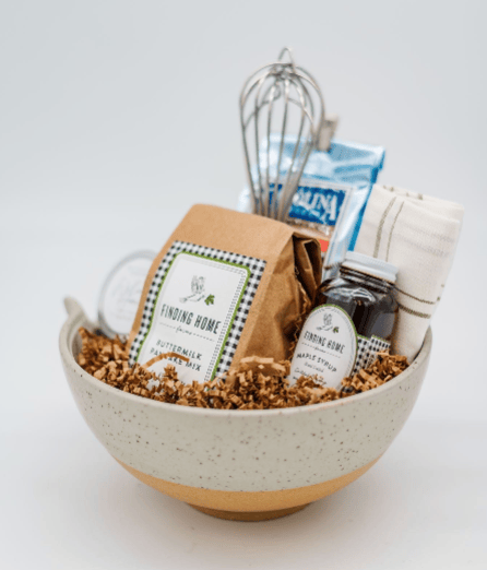 Gift basket with granola, milk, and other items in a bowl on a white background