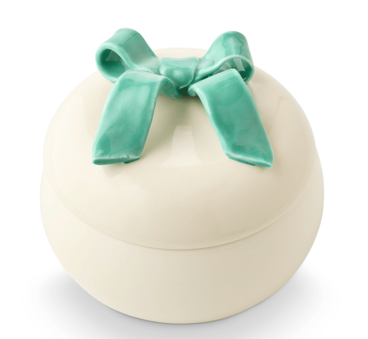 Round beige container with a green bow on a white background
