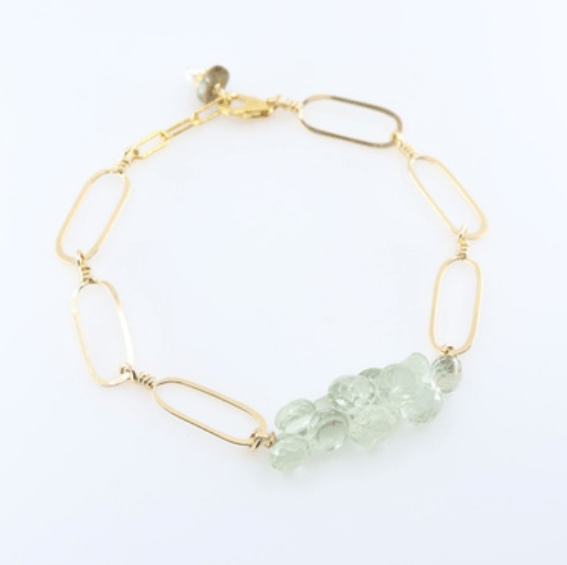 Gold bracelet with green gemstones on a white background