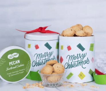 Christmas-themed cookie tins with cookies and a small container on a white background