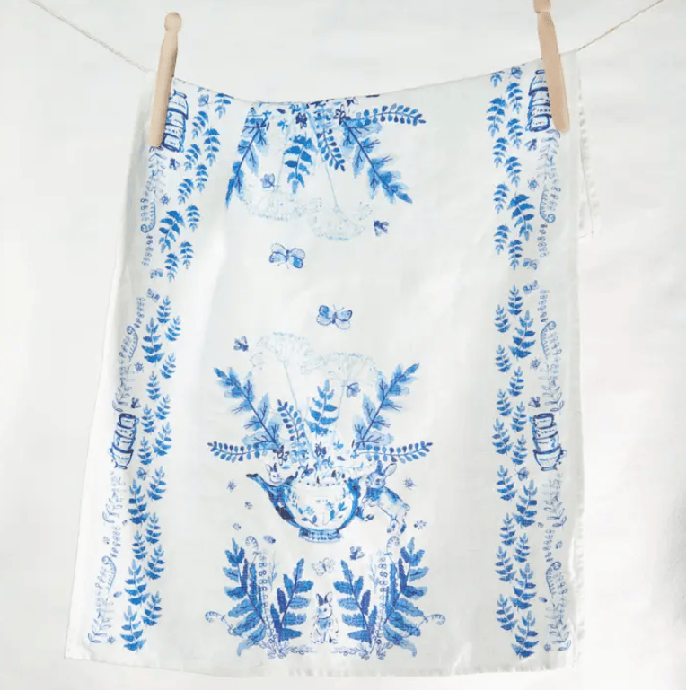White towel with blue floral pattern hanging on a wooden rack against a white background