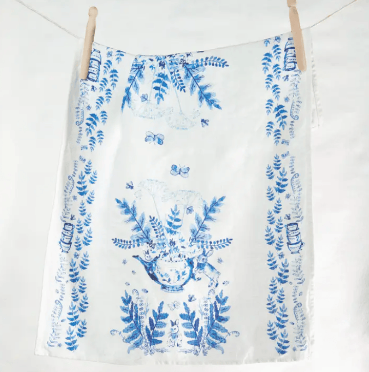 White towel with blue floral pattern hanging on a wooden rack against a white background