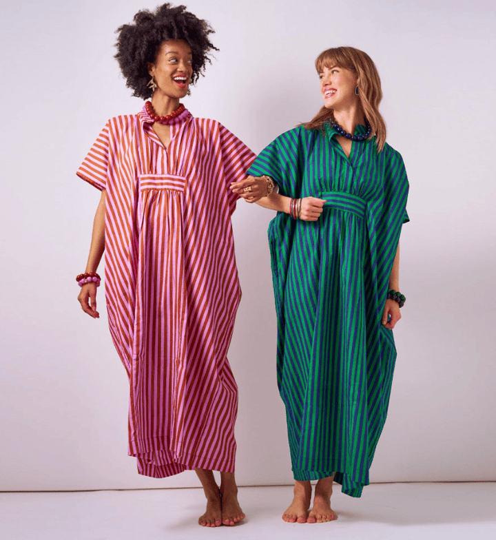 Two women wearing colorful striped kaftans against a white background