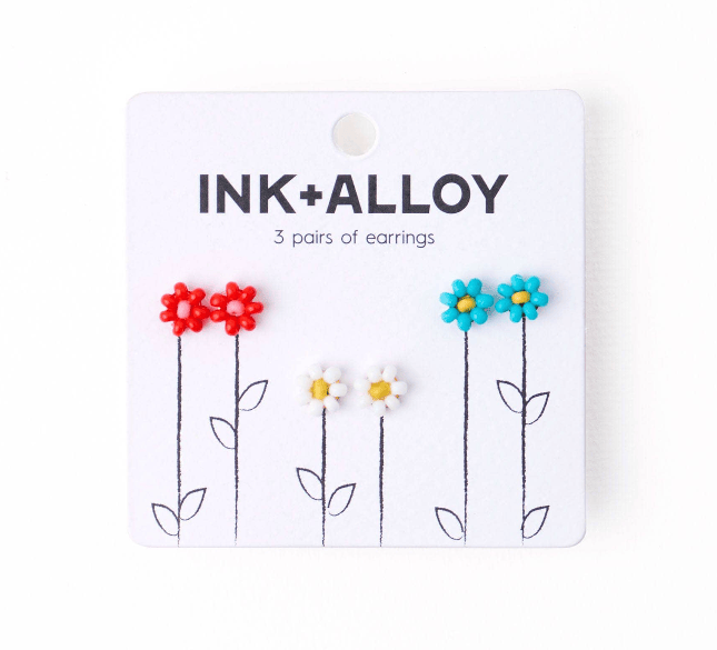 Packaged earrings with flower designs on a white background, featuring the brand 'INK+ALLOY'.