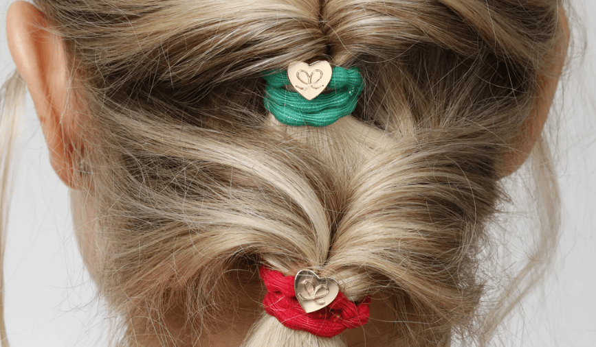 Close-up of a person's hair with green and red hair ties featuring heart designs.