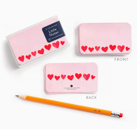 Pink notepad with heart designs and a pencil on a white background