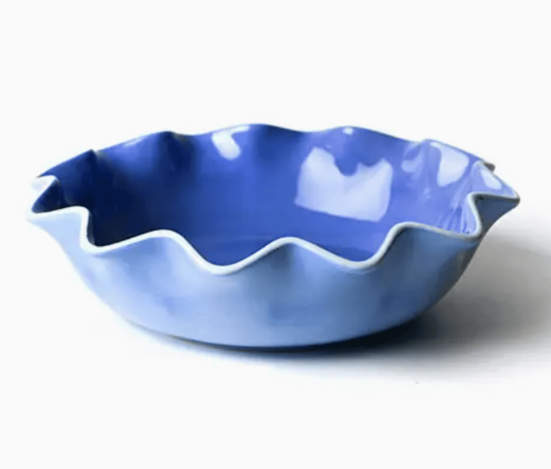Blue ceramic bowl with wavy edge on a white background