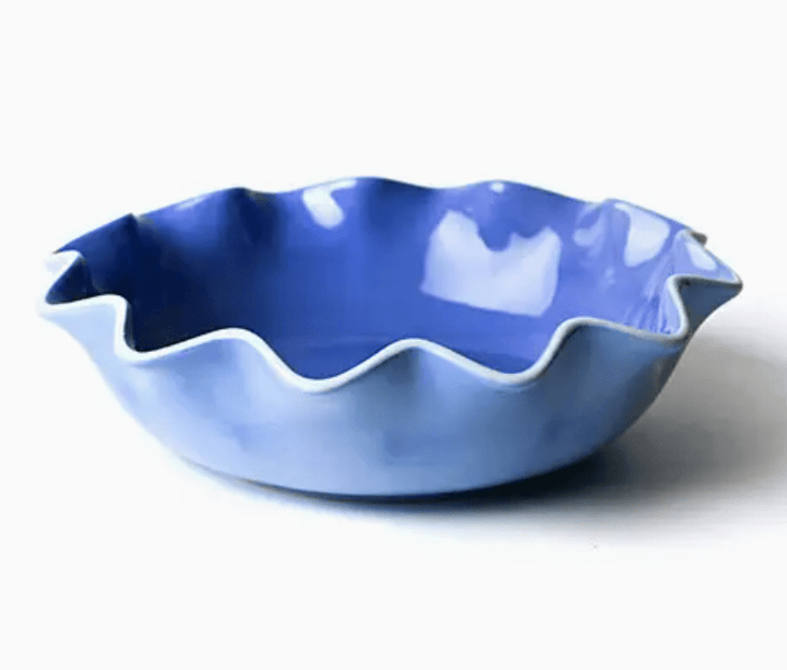Blue ceramic bowl with wavy edge on a white background