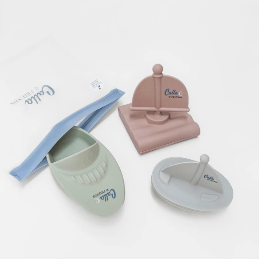Three small boat-shaped silicone bath toys shown with their light blue storage pouch on a clean white background.