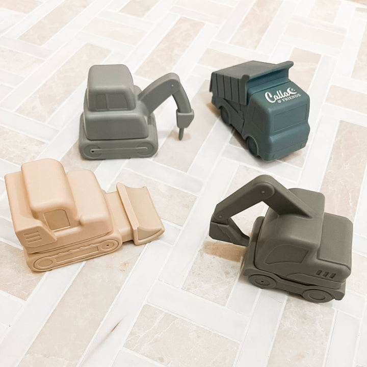 Four toy construction vehicles on a tiled floor