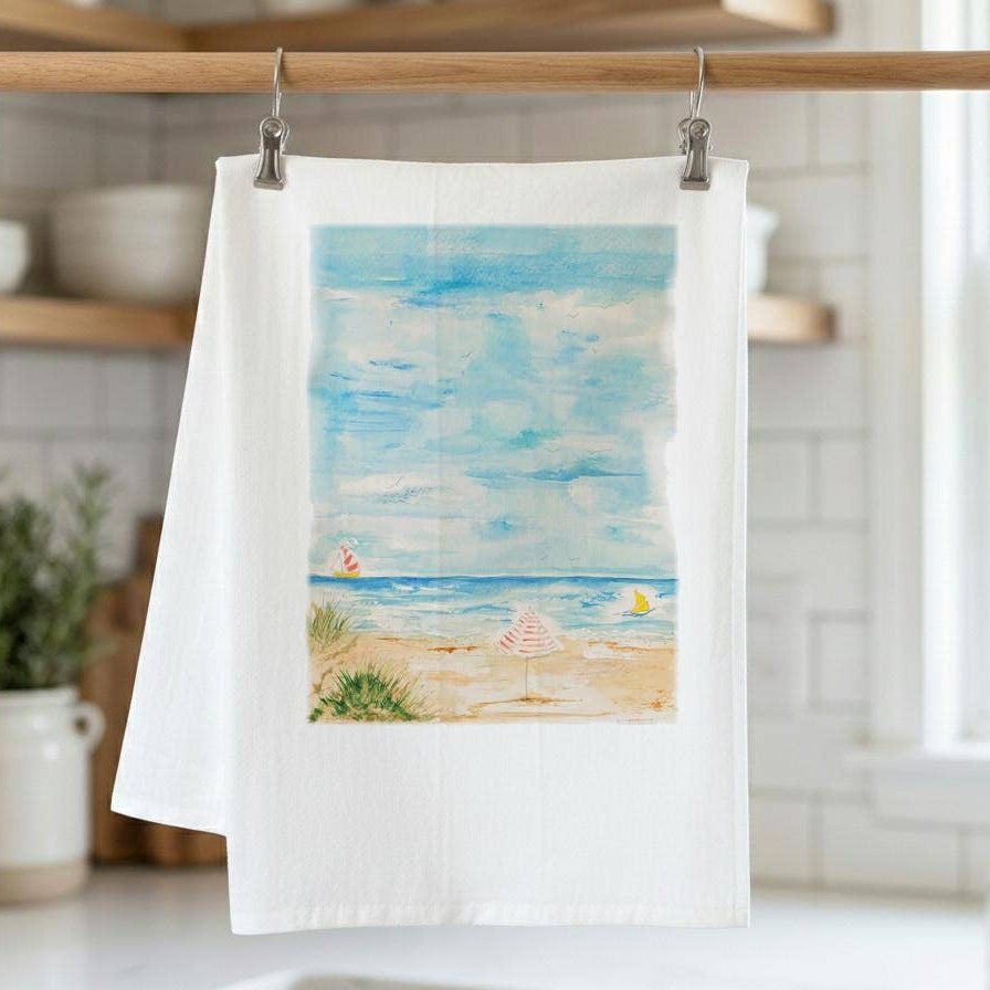 Tea towel with beach scene hanging on a rack in a kitchen