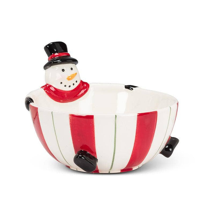 A ceramic holiday bowl shaped like a snowman, featuring a white body with red vertical stripes, a black top hat, a red scarf, and small black hands holding the bowl.