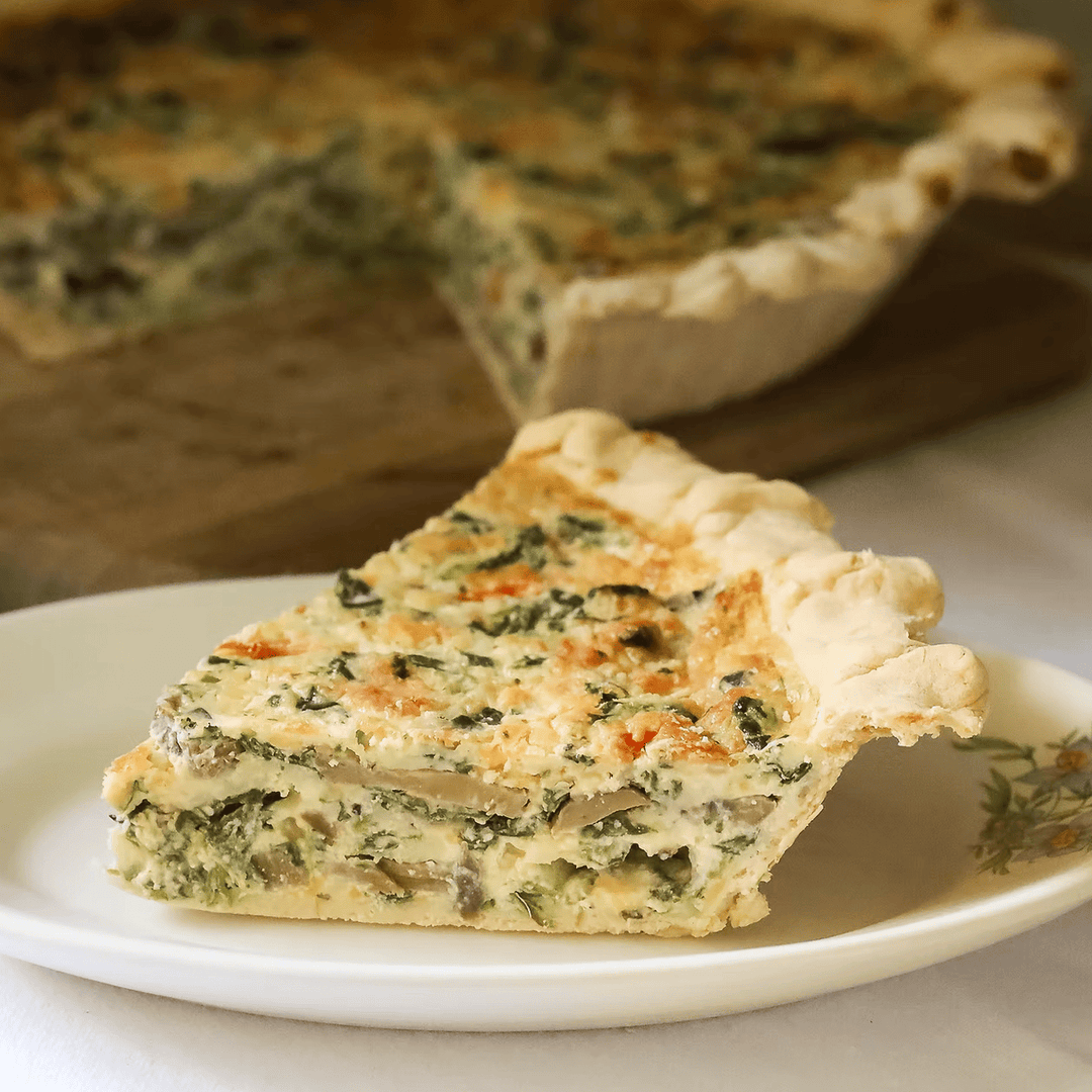 Slice of a vegetable and egg quiche on a white plate with rest of pie in background