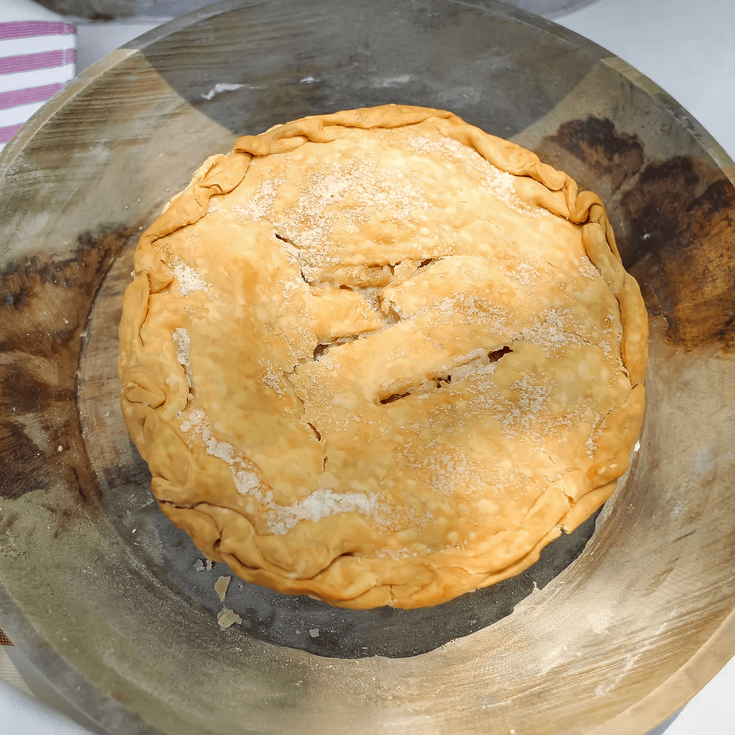 Baked pie on a wooden board with a striped cloth in the background