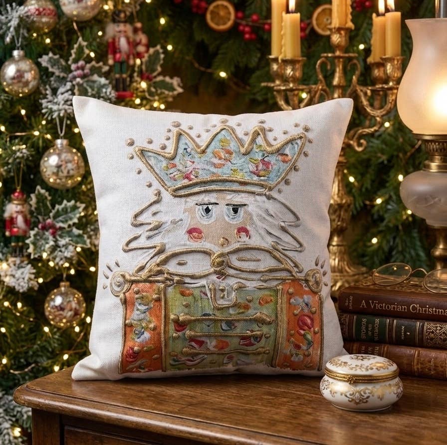 Decorative pillow with embroidered design of a nutcracker in front of a Christmas tree.