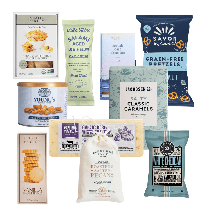 A collection of assorted snack and candy products arranged together on a plain white background, including bags and boxes of pretzels, caramels, cookies, chocolate, and crackers from brands such as Rustic Bakery, Young's, Salt & Stone, Jacobsen & Co, and Schürme's.