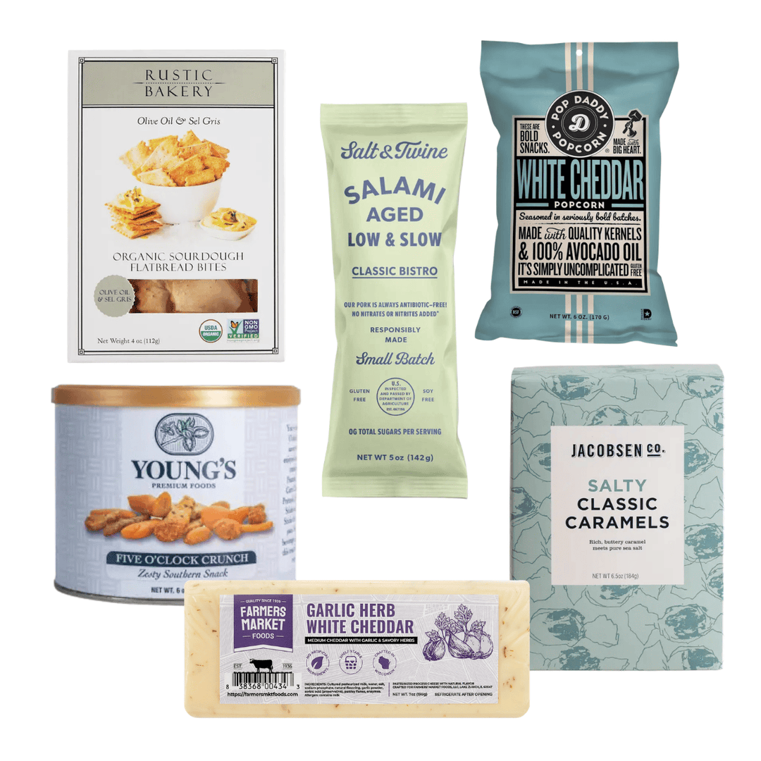 A curated assortment of gourmet snacks and cheeses from multiple brands, including Rustic Bakery, Salt & Tine, Good Food Company, Young's, and Jacobsen & Co., arranged together on a plain white background.