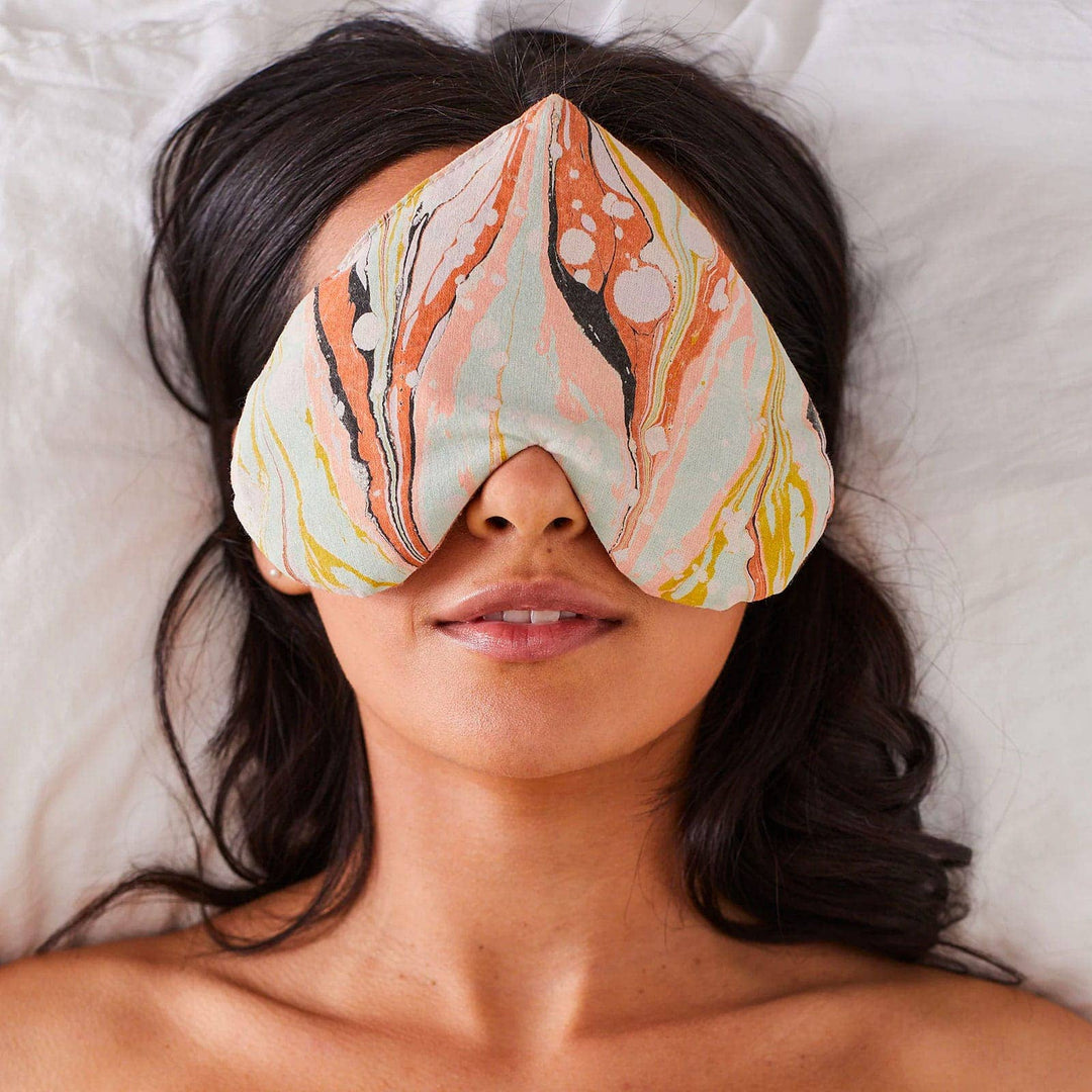 Woman wearing a colorful patterned eye mask on a soft surface
