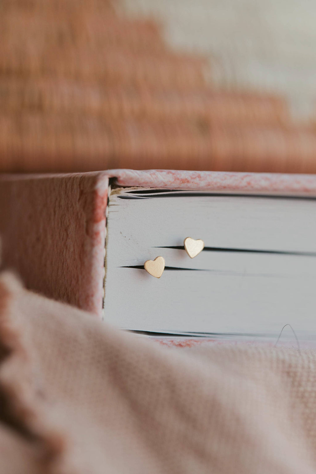 Heart-shaped gold earrings on a white surface with a blurred background