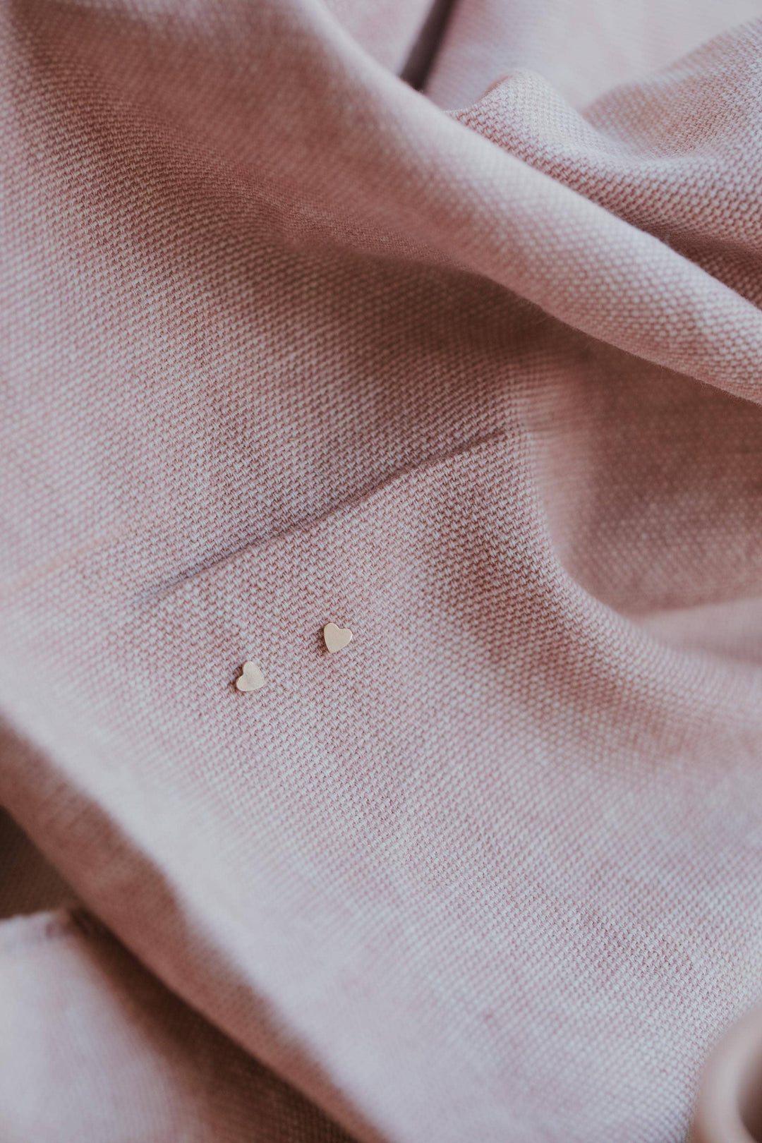 Close-up of pink fabric with small heart shaped earrings