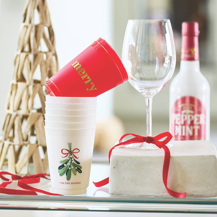 Wine glass, bottle, and festive cups on a table with a blurred background