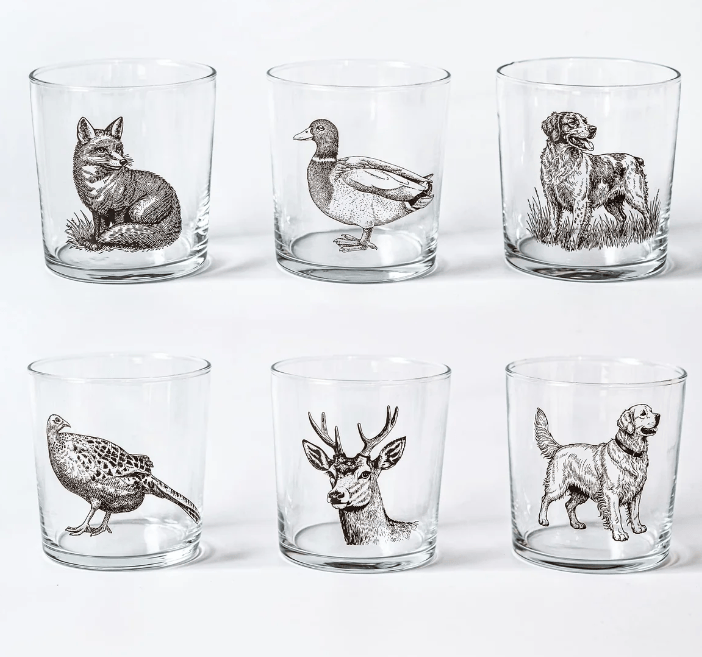 Six clear lowball glasses arranged in two rows on a white background, each printed with a different animal illustration in dark gray: a fox, duck, dog, pheasant, deer, and golden retriever.
