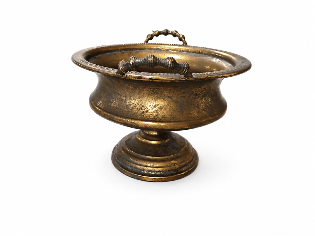 An antique-style brass pedestal bowl with a matching top handle, shown on a plain white background.