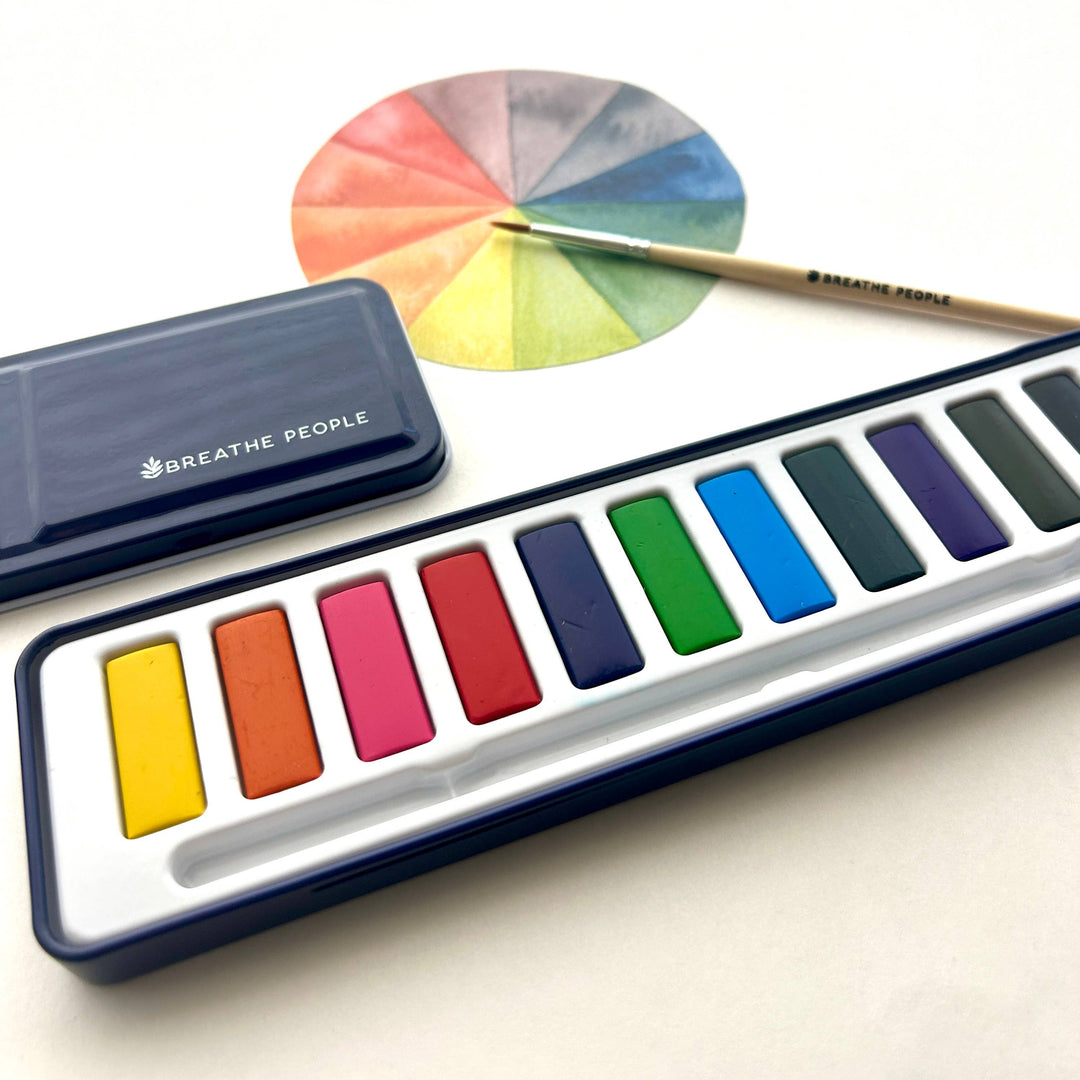 Set of watercolor paints with a color wheel and brush on a white background