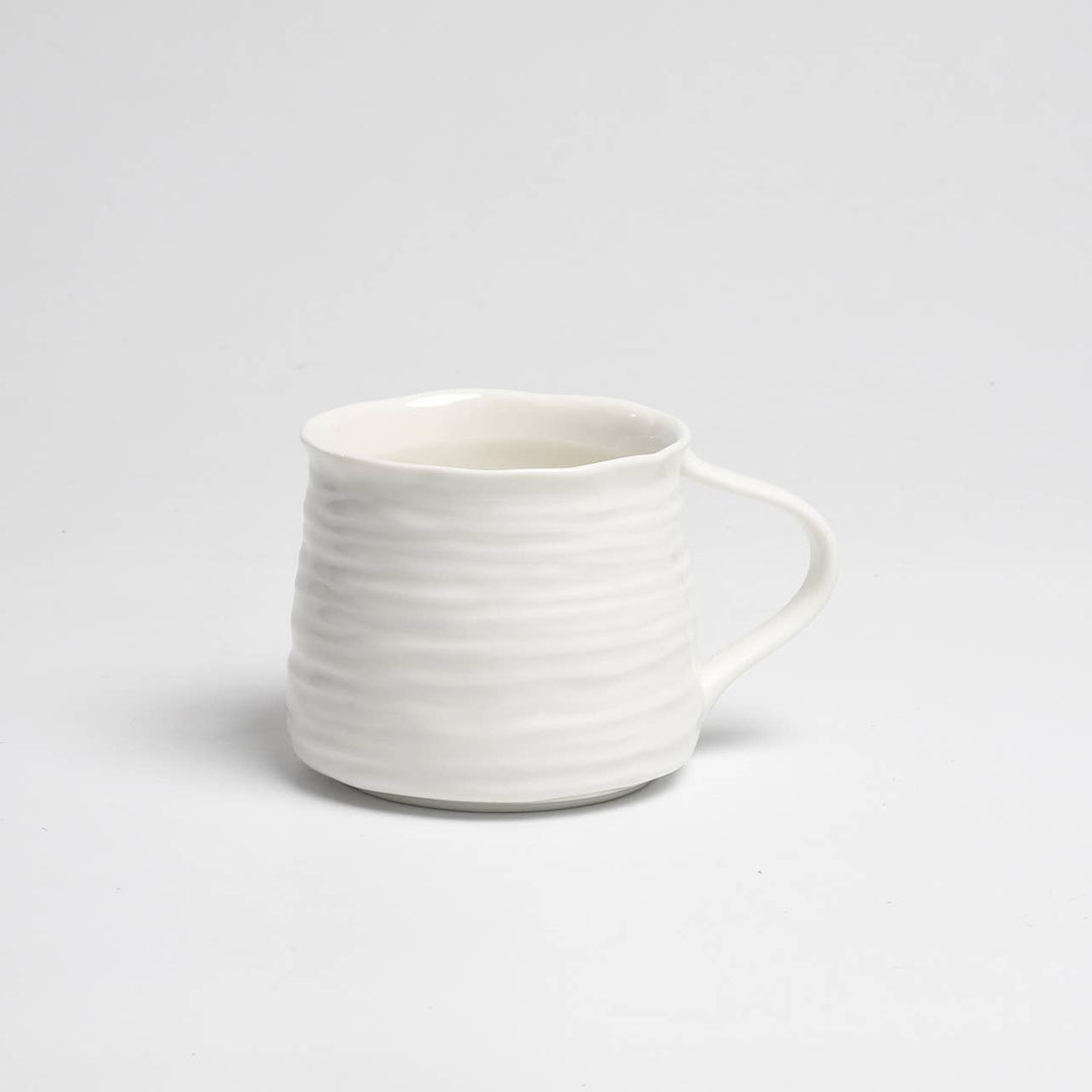 White ceramic mug with a textured design on a light gray background