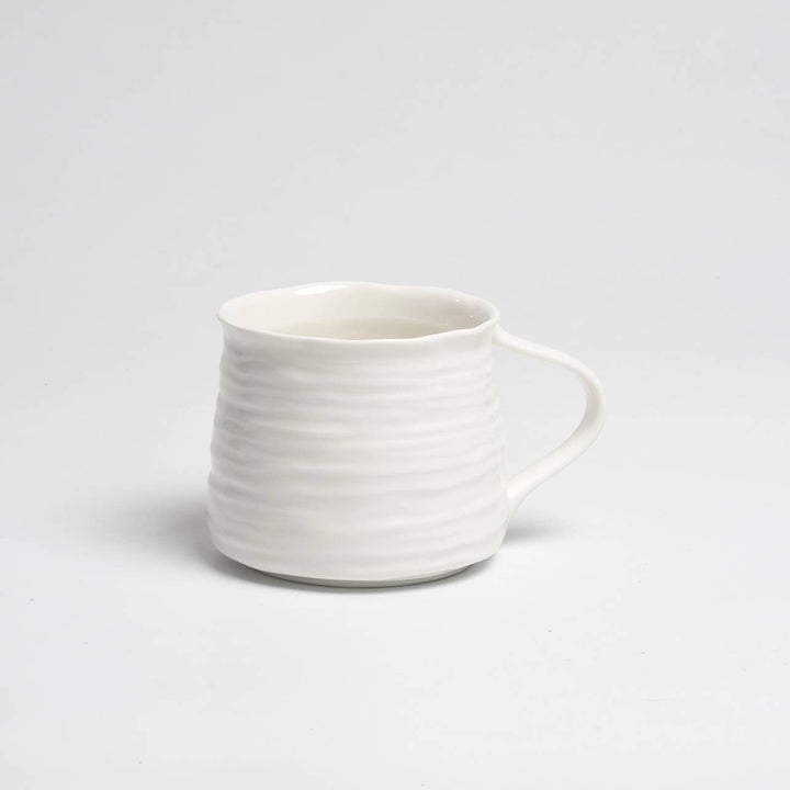 White ceramic mug with a textured design on a light gray background