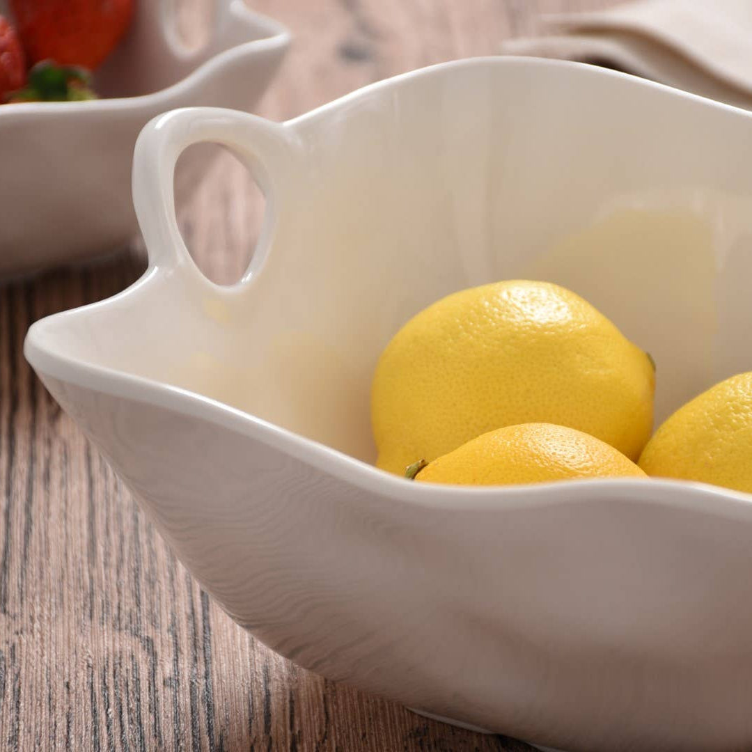 White ceramic bowl with lemons on a wooden surface