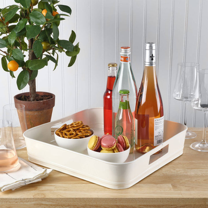 Tray with snacks and drinks on a wooden table next to a potted plant.