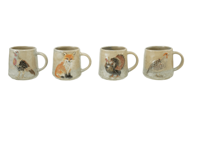 Four ceramic mugs lined up in a row, each decorated with a different animal illustration including a chicken, fox, turkey, and pheasant, on a plain white background.