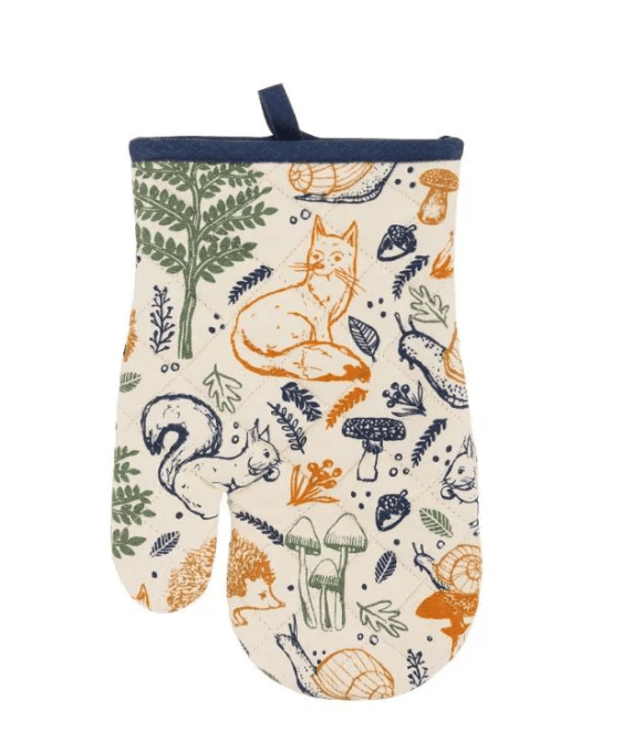 A single oven mitt with a woodland forest pattern featuring a fox, squirrel, mushrooms, and leaves on an off-white background, finished with a navy blue top trim and hanging loop.