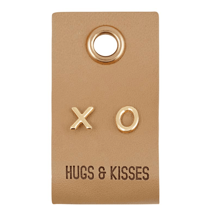 Gold earrings with 'XO' on a brown card labeled 'Hugs & Kisses' on a white background