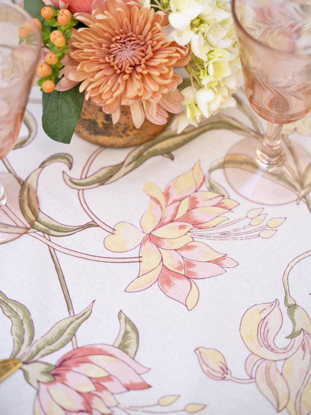 Decorative tablecloth with floral patterns and a vase of flowers on a table.