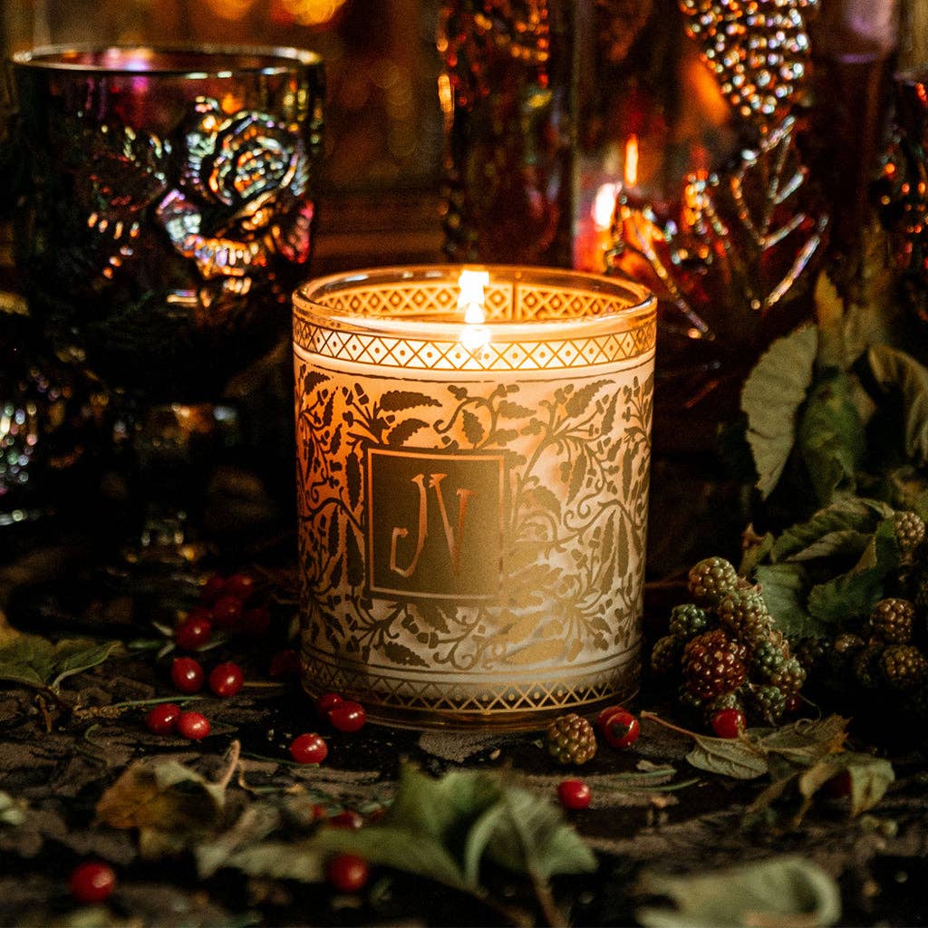 Decorative candle with intricate design and 'ELV' logo, surrounded by berries and leaves.