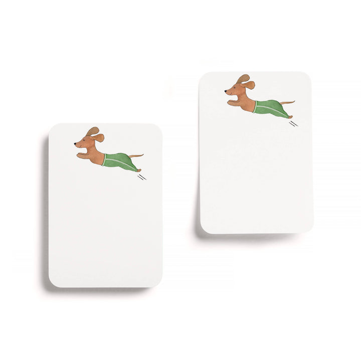 Two white sticky notepads with  dachshund in green track pants artwork on a white background